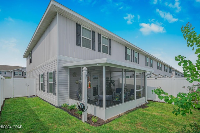 back of house featuring a yard and a sunroom