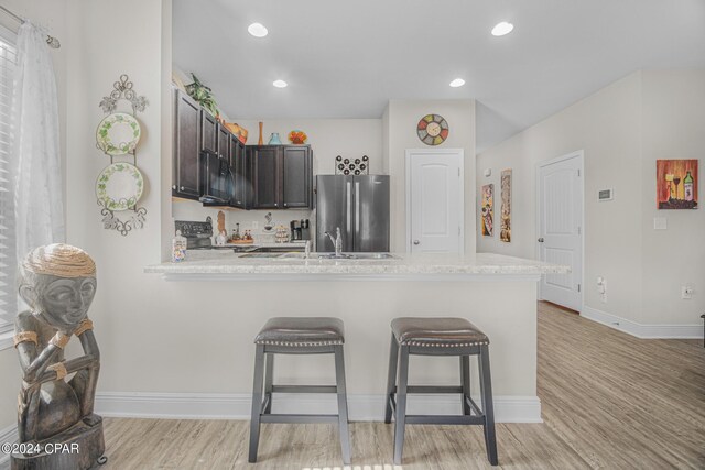 kitchen with light hardwood / wood-style flooring, light stone countertops, stainless steel fridge, dark brown cabinetry, and sink