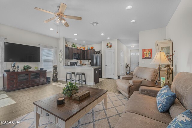 living room with ceiling fan and light hardwood / wood-style flooring