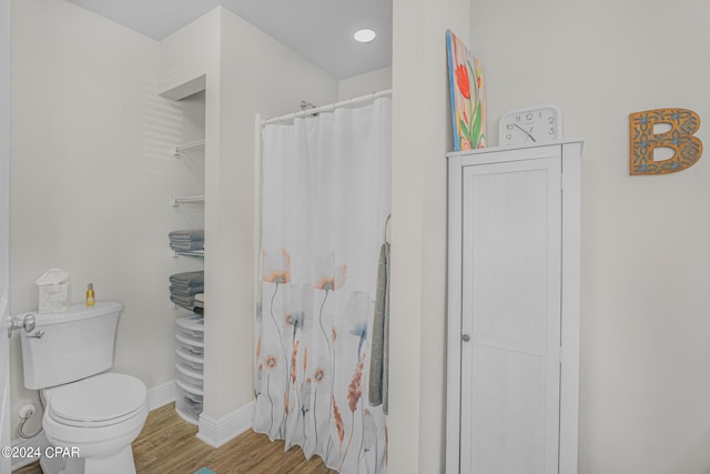 bathroom with hardwood / wood-style floors, toilet, and walk in shower