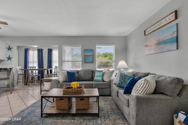 living room with tile patterned flooring, ceiling fan, and a textured ceiling