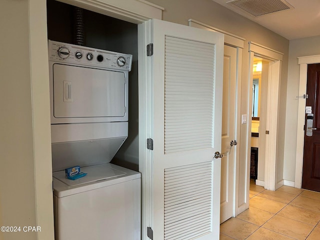 washroom with light tile patterned flooring and stacked washer / dryer