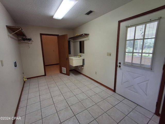 laundry room featuring washer hookup, sink, light tile patterned floors, and a textured ceiling