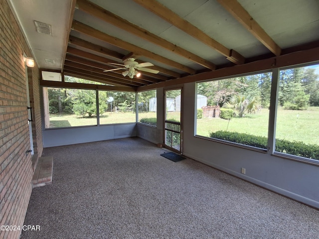 unfurnished sunroom with vaulted ceiling with beams, a wealth of natural light, and ceiling fan