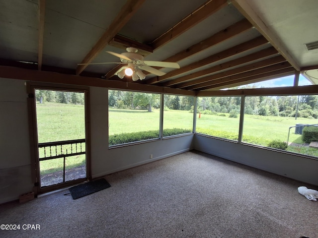 unfurnished sunroom featuring beamed ceiling, a wealth of natural light, and ceiling fan