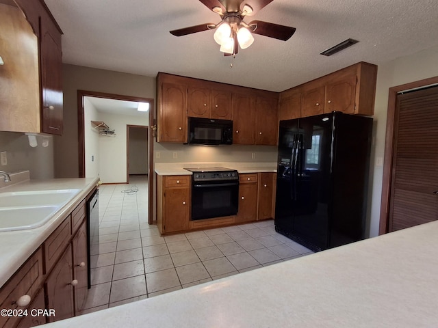 kitchen with sink, light tile patterned floors, ceiling fan, black appliances, and a textured ceiling