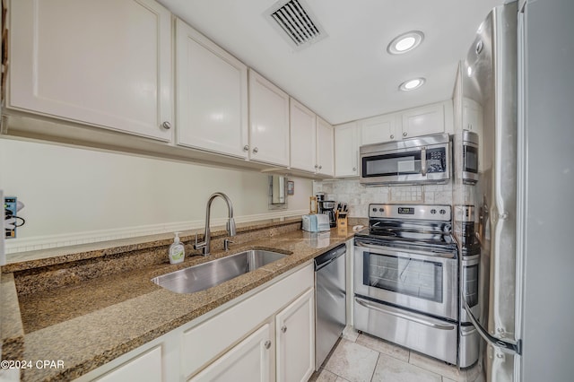 kitchen with white cabinets, appliances with stainless steel finishes, stone counters, and sink