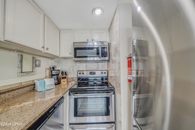 kitchen with white cabinets, appliances with stainless steel finishes, tasteful backsplash, and light stone countertops