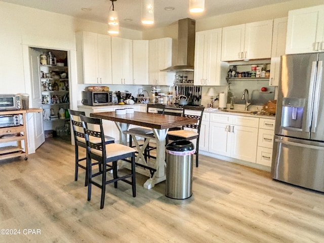 kitchen featuring stainless steel appliances, white cabinets, wall chimney exhaust hood, sink, and light hardwood / wood-style floors