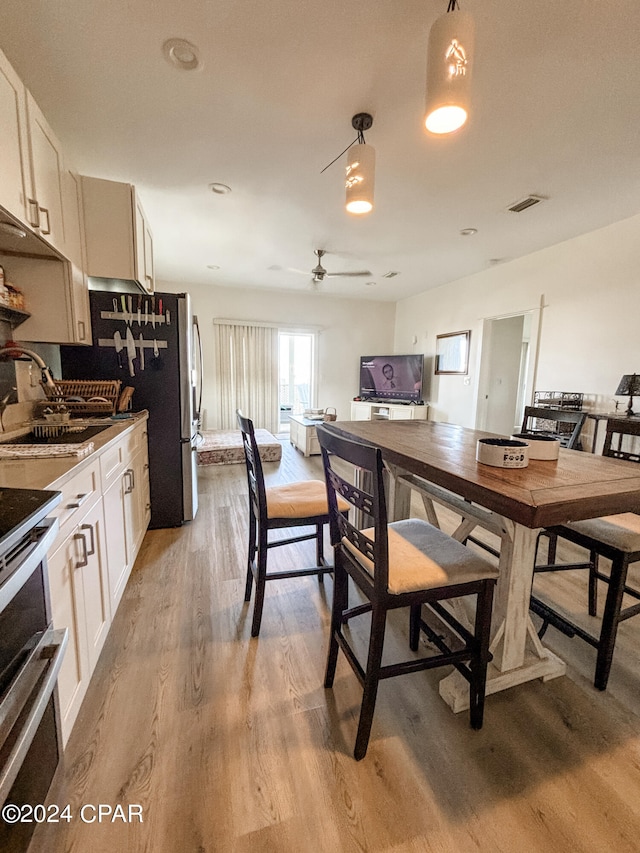 dining room with sink, light wood-type flooring, and ceiling fan