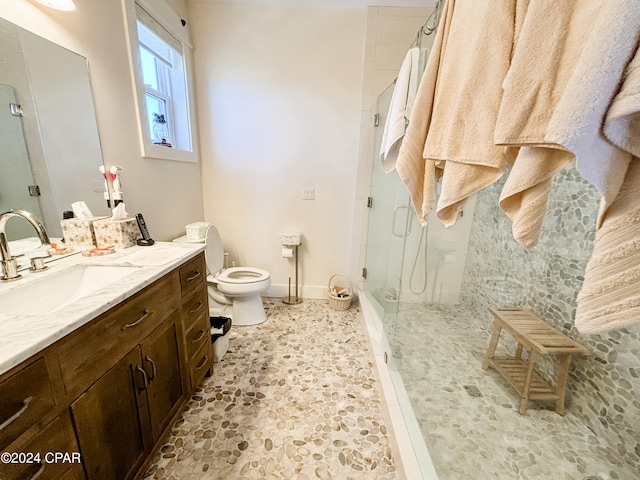 bathroom with tiled shower, vanity, tile patterned flooring, and toilet