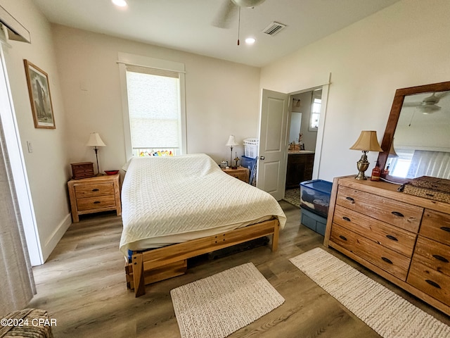 bedroom with hardwood / wood-style flooring, connected bathroom, and ceiling fan