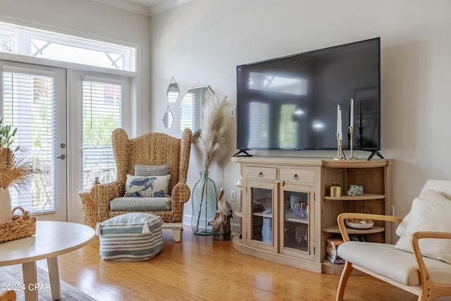 sitting room featuring ornamental molding, light hardwood / wood-style flooring, and french doors