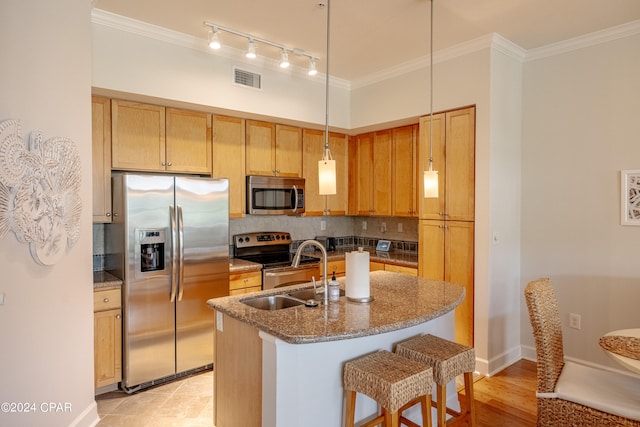 kitchen with pendant lighting, a kitchen island with sink, stainless steel appliances, backsplash, and ornamental molding