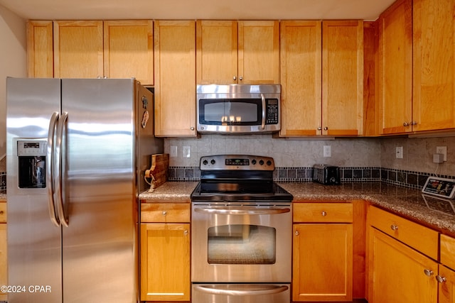 kitchen featuring appliances with stainless steel finishes, decorative backsplash, and dark stone counters