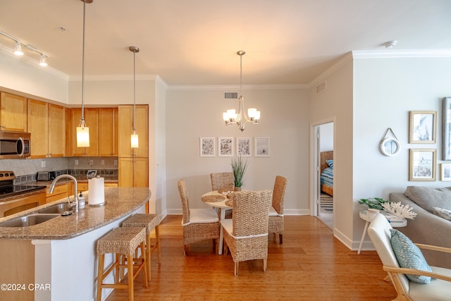 kitchen featuring backsplash, light wood-type flooring, decorative light fixtures, sink, and a notable chandelier