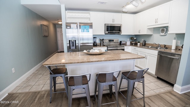 kitchen with a center island, light hardwood / wood-style floors, white cabinetry, and appliances with stainless steel finishes