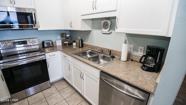 kitchen featuring sink, appliances with stainless steel finishes, light tile patterned flooring, light stone counters, and white cabinetry