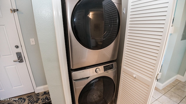 laundry area featuring light tile patterned floors and stacked washing maching and dryer