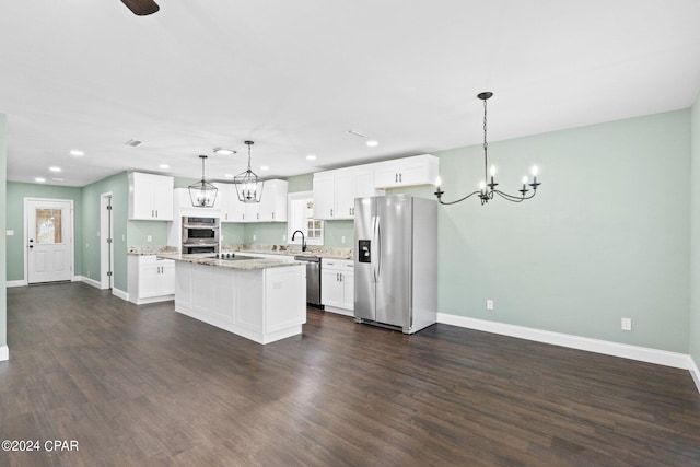 kitchen with pendant lighting, an island with sink, appliances with stainless steel finishes, and dark wood-type flooring