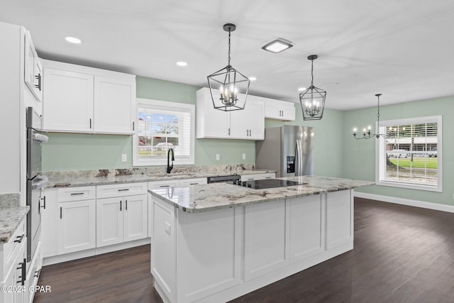 kitchen featuring white cabinets, stainless steel appliances, a kitchen island, and plenty of natural light