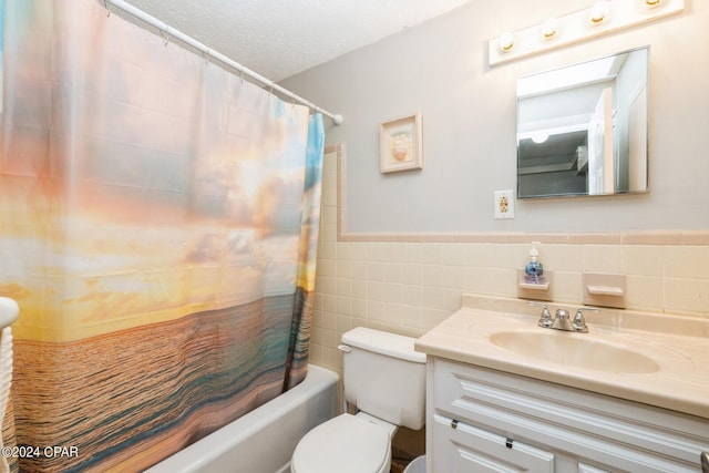 bathroom featuring a textured ceiling, toilet, vanity, tile walls, and wainscoting