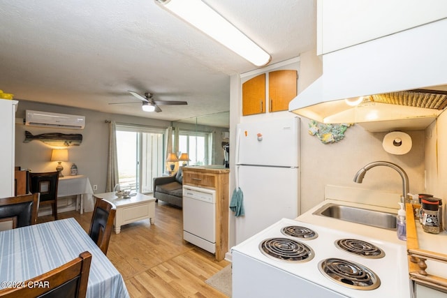 kitchen with white appliances, custom exhaust hood, an AC wall unit, light wood-style floors, and a sink