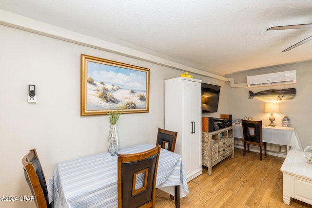 dining room with an AC wall unit, a ceiling fan, and light wood-style floors