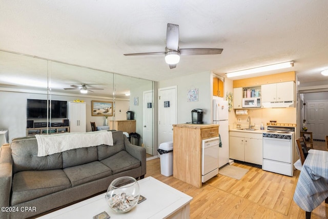 living room featuring light wood-type flooring, ceiling fan, and a textured ceiling