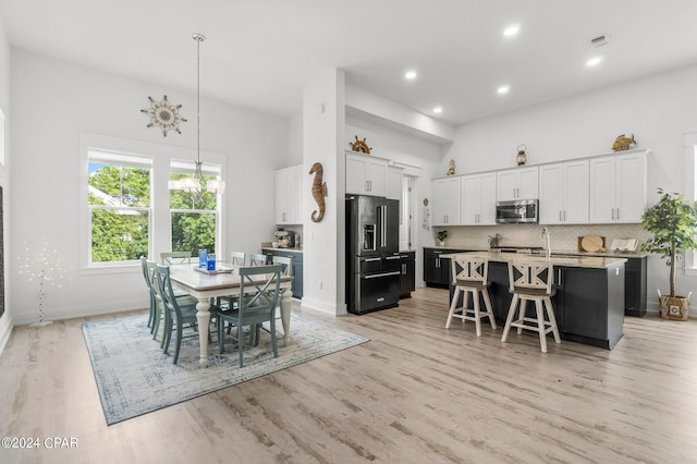 dining space featuring a towering ceiling and light hardwood / wood-style flooring