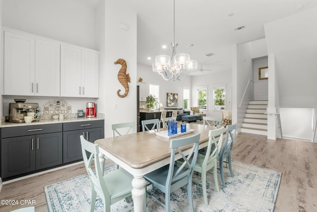 dining space with an inviting chandelier, light wood-type flooring, and a high ceiling