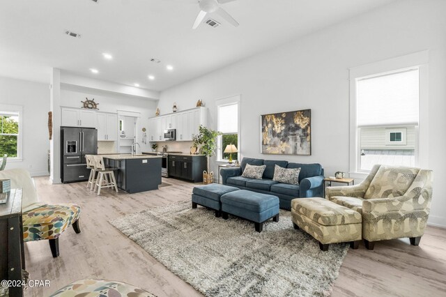 living room with light wood-type flooring and ceiling fan