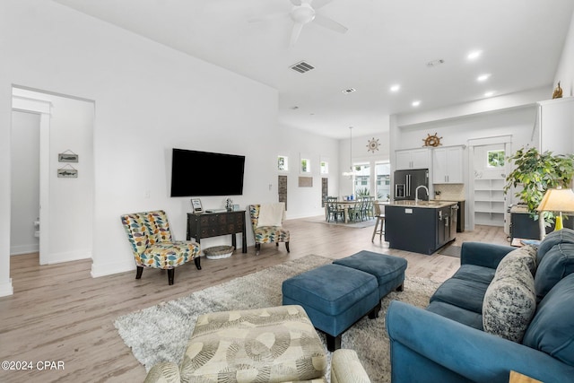 living room with light hardwood / wood-style floors, sink, and ceiling fan