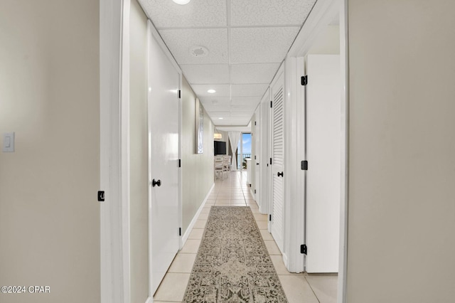 hall with a drop ceiling and light tile patterned floors