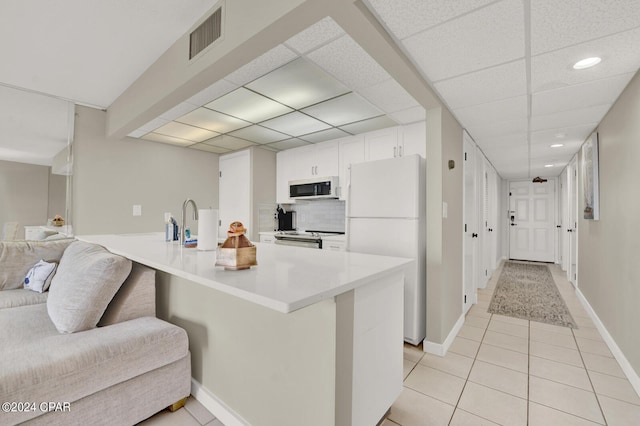 kitchen featuring a breakfast bar area, white cabinetry, kitchen peninsula, white appliances, and backsplash