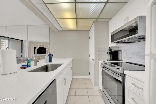 kitchen featuring sink, light tile patterned floors, stainless steel appliances, tasteful backsplash, and white cabinets