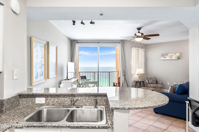 kitchen featuring sink, light tile patterned floors, ceiling fan, and light stone countertops