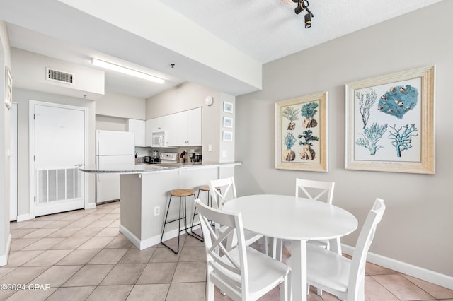 dining area with a textured ceiling and light tile patterned floors