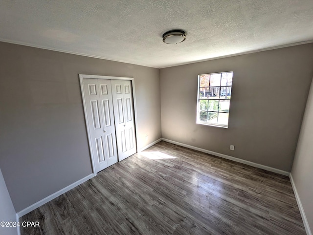 unfurnished bedroom featuring dark hardwood / wood-style floors, a textured ceiling, and a closet