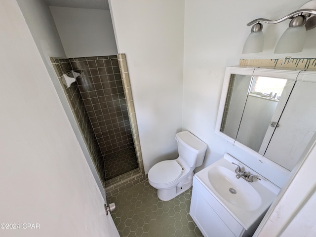 bathroom with vanity, toilet, and tiled shower