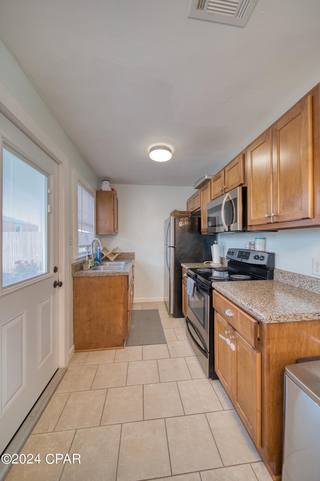 kitchen featuring stainless steel appliances, brown cabinetry, visible vents, and a sink