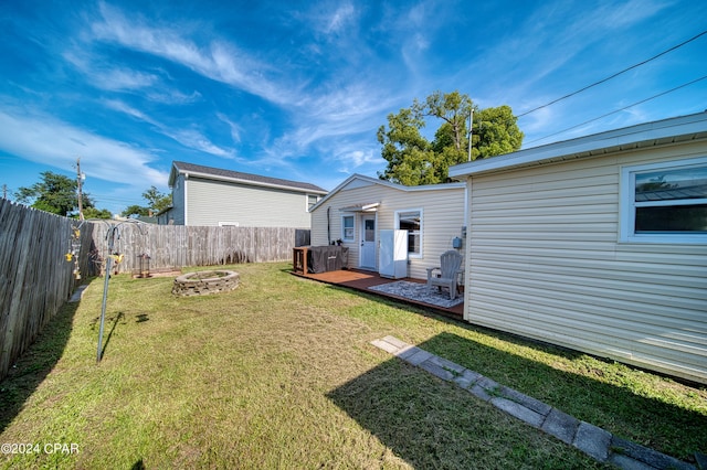 view of yard featuring a fire pit, a deck, and a fenced backyard