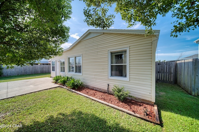 view of side of home featuring a fenced backyard, a yard, and a patio