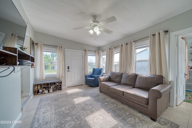 living area featuring light tile patterned floors, ceiling fan, a textured ceiling, and baseboards