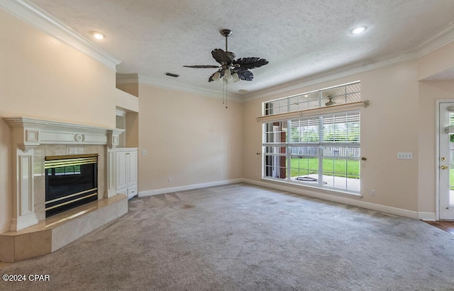 unfurnished living room featuring ceiling fan, a tiled fireplace, crown molding, and light colored carpet