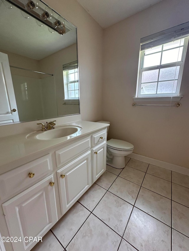 bathroom featuring tile patterned flooring, toilet, vanity, and walk in shower