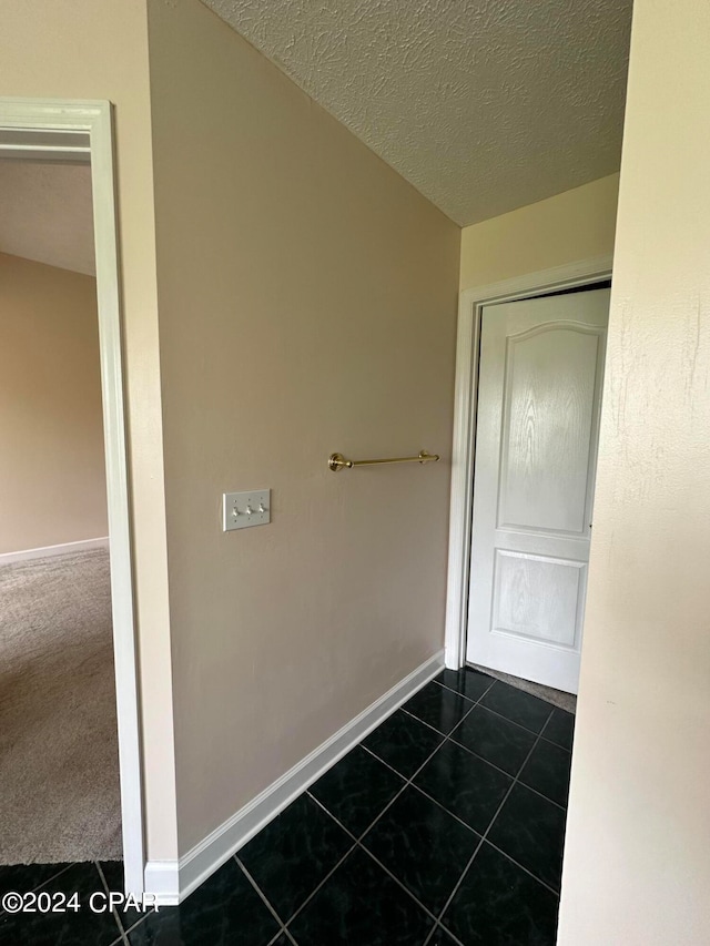 corridor with dark tile patterned flooring and a textured ceiling