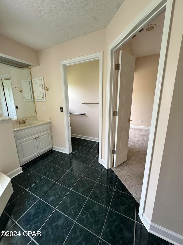 bathroom with a textured ceiling, vanity, and tile patterned floors