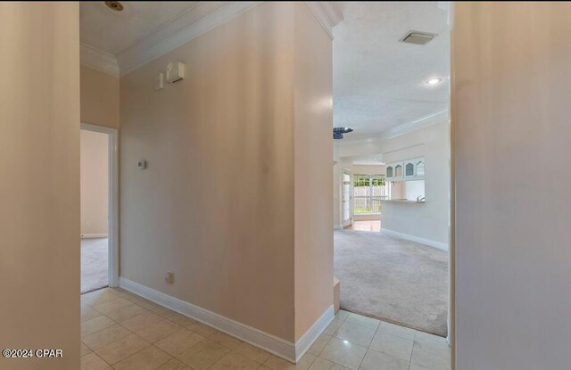 corridor with light tile patterned flooring and crown molding