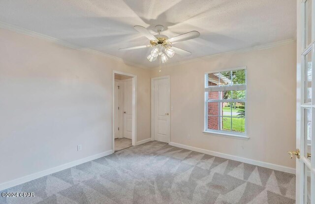 spare room featuring light colored carpet, ornamental molding, and ceiling fan